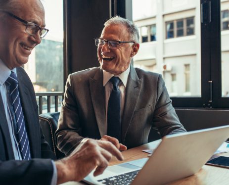 Two older businessmen in suits having a light conversations Two older businessmen in suits having a light conversations
